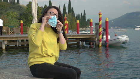 slow motion shot of young woman with glasses in a scenic location putting her face covering on