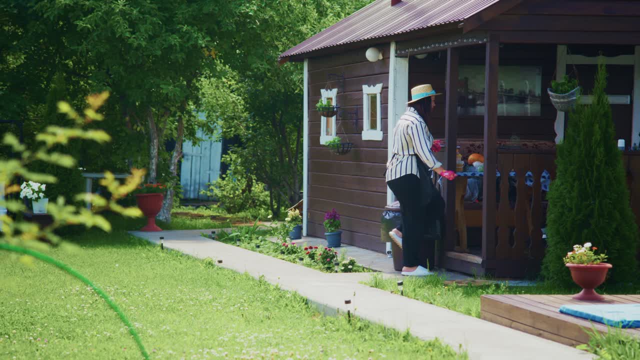 Joyful woman in garden wearing hat and overalls, celebrating life with vibrant greenery around