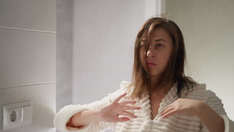 young lady straightens dark hair with hands in light bathroom. brunette lady straightens dark hair after shower in cozy light bathroom slow motion