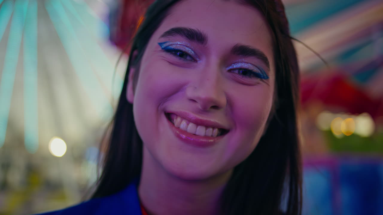 una chica alegre disfrutando de un close-up en el parque de luna. modelo de fiesta descansando en una feria iluminada.
