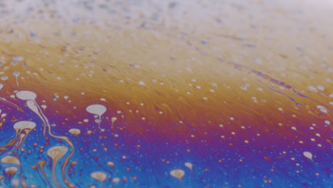 macro shot of a viscous liquid with small white oil drops on the surface