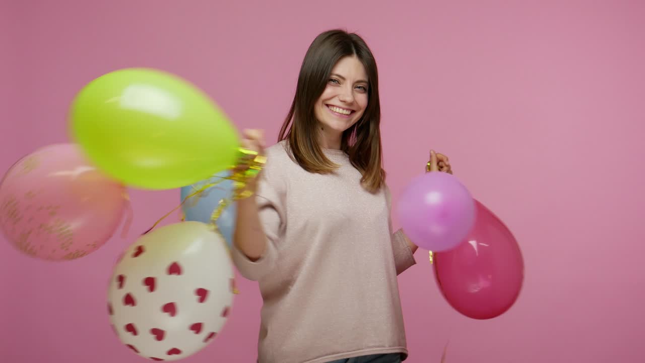 alegre feliz enérgica mujer morena riendo y bailando con coloridos globos de aire, disfrutando de la fiesta de cumpleaños