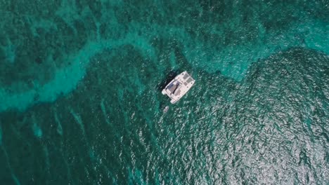 Vista-Aérea-De-Drones-De-Arriba-Hacia-Abajo-De-La-Isla-Desierta-De-Bahamas-Con-Un-Velero-Solitario-Y-Agua-Cristalina