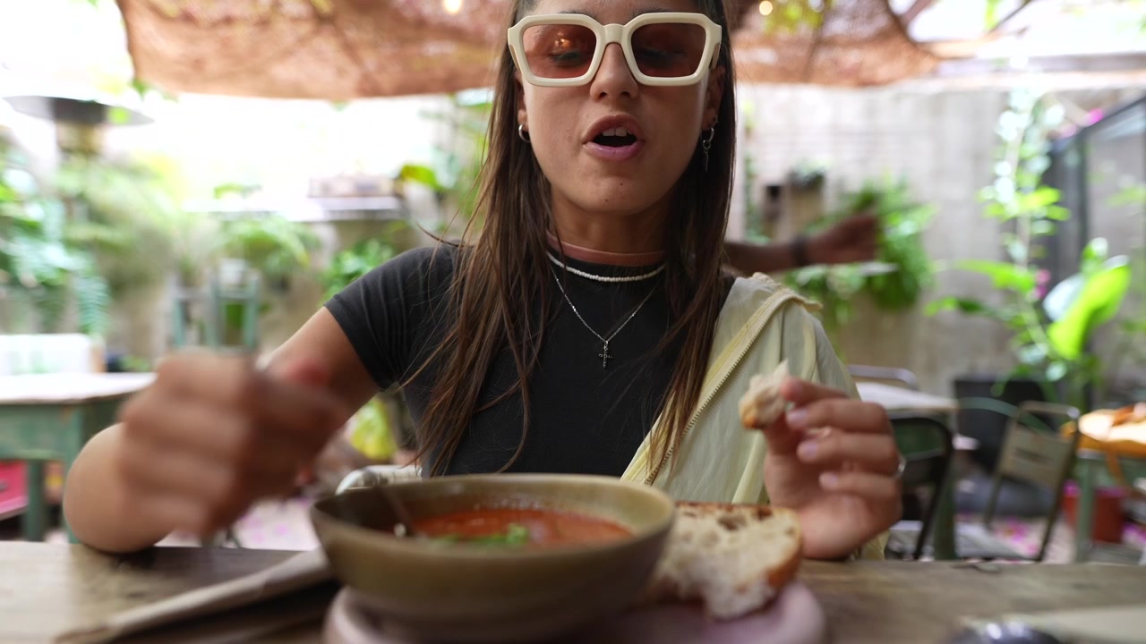 Young Woman Eating Tomato Soup and Bread in Outdoor Cafe