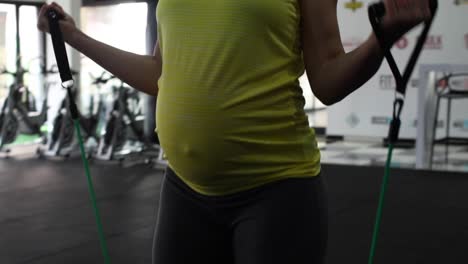 modelo de fitness femenino embarazada haciendo ejercicio de peso corporal en un gimnasio para mantenerse en forma durante su tercer trimestre de embarazo