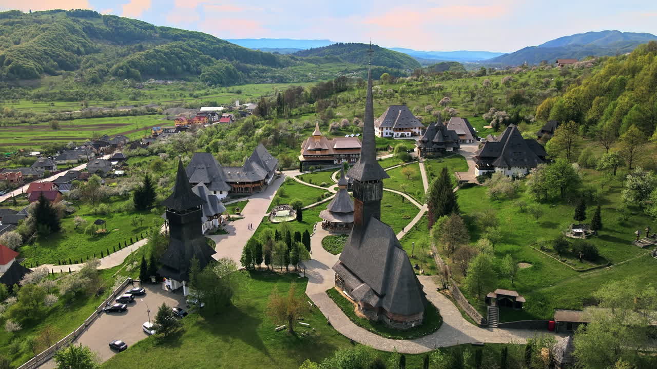 Luftaufnahme mit einer Drohne des Barsana-Klosters, Rumänien. Gebäude, Garten mit Menschen, Hügel mit Wald bedeckt
