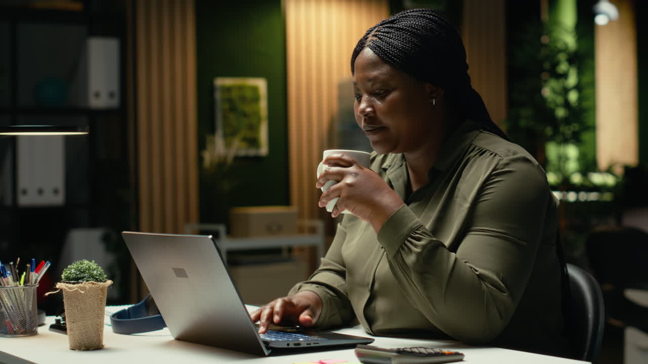 African american analyst drinking a coffee cup to keep working after hours
