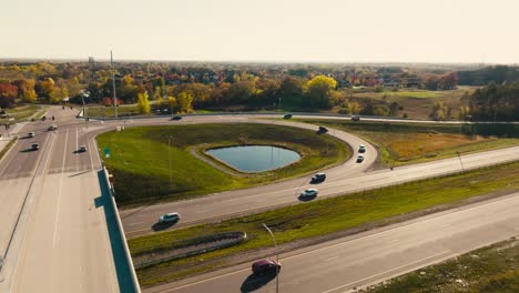 aerial drone shot of a highway overpass entrance and exit ramp and a bridge with cars moving on the highway on a sunny day