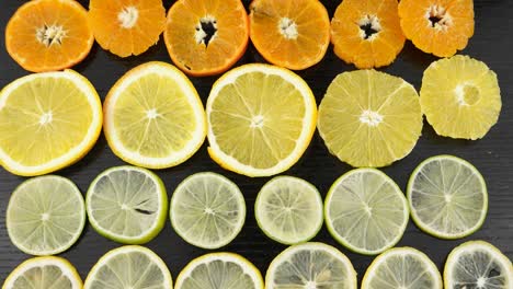 citrus fruits in a section on a black table. lemon, lime, orange, blood orange, mandarin