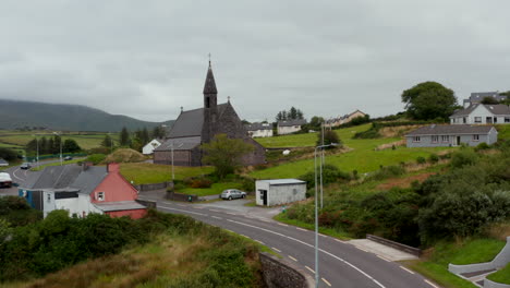 Rising-shot-of-village-with-historic-religious-dominant.-Old-stone-church-standing-at-main-road-in-village.-Ireland