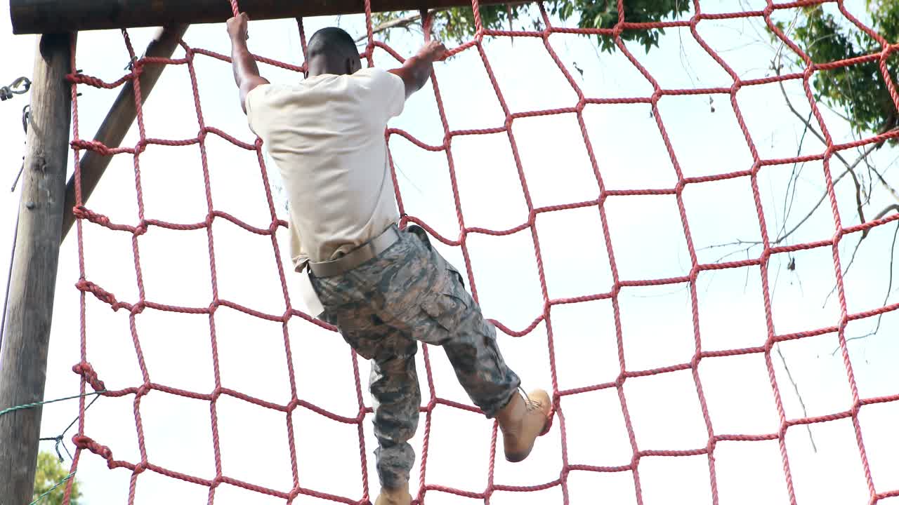 soldado militar subiendo la cuerda durante un curso de obstáculos
