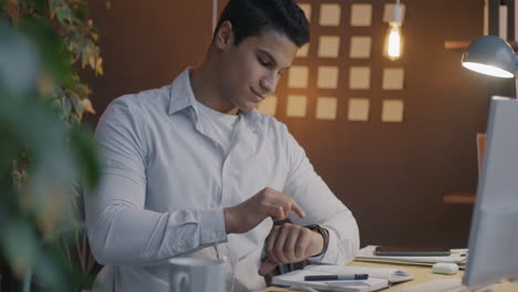 man checking smartwatch in office