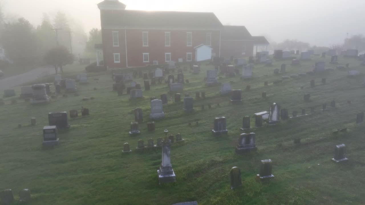 viejo cementerio en frente de la iglesia roja envuelto en una niebla extraña, aérea