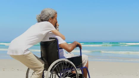 Side-view-of-active-senior-African-American-woman-embracing-disabled-senior-man-on-the-beach-4k