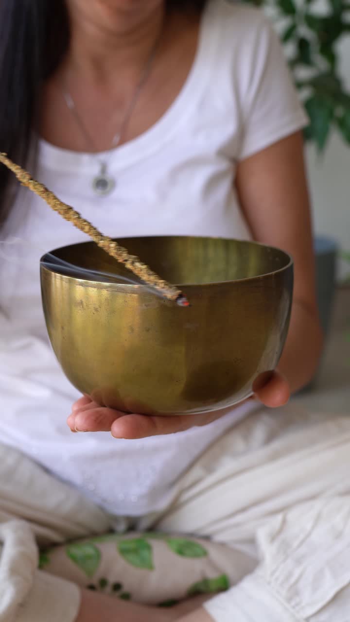Woman Cleansing Tibetan Singing Bowl With Burning Incense In Serene, Meditative Atmosphere. closeup, vertical shot