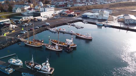 a picturesque aerial view captures the charming harbor of húsavík, iceland, bustling with various boats and ships docked along the waterfront