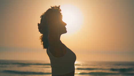 ragazza sportiva che riscalda il corpo davanti all'alba da vicino. silhouette donna atletica.