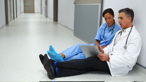 Doctors-discussing-over-digital-tablet-in-corridor