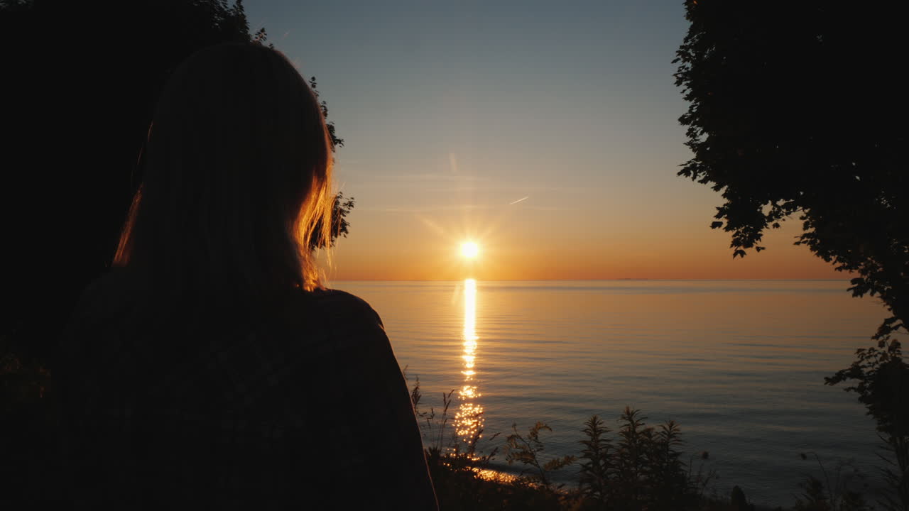 女性観光客が熱帯地方の海に沈む夕日を眺める