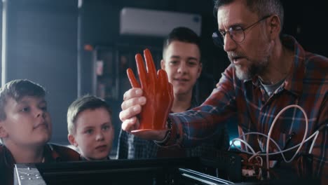 teacher demonstrating 3d printed hand model to students