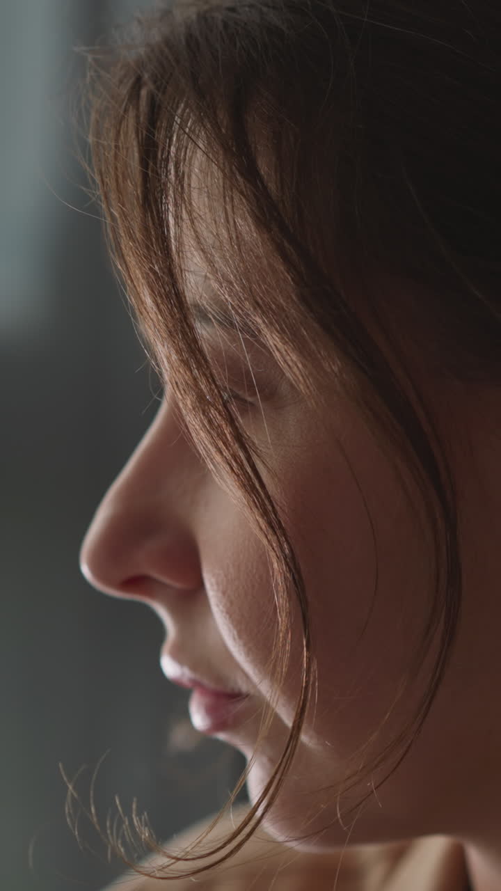 una giovane donna pensierosa guarda il traffico per strada seduta a casa. una donna fa l'occhiolino guardando fuori dalla finestra dalla stanza in un appartamento accogliente. una casalinga rilassata si riposa