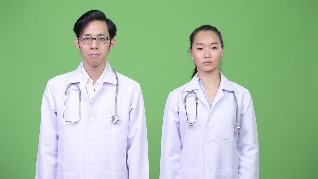 Young Asian couple doctors with stop gesture together