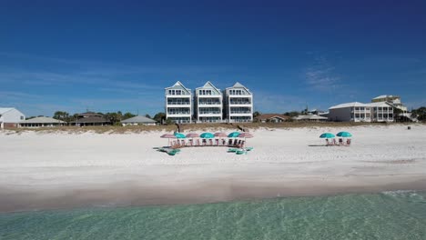 beachfront luxury homes with beach umbrellas and chairs on white sand at summer. panama city beach in florida. wide drone shot