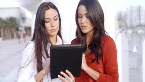 Young-woman-looking-at-a-tablet-outdoors