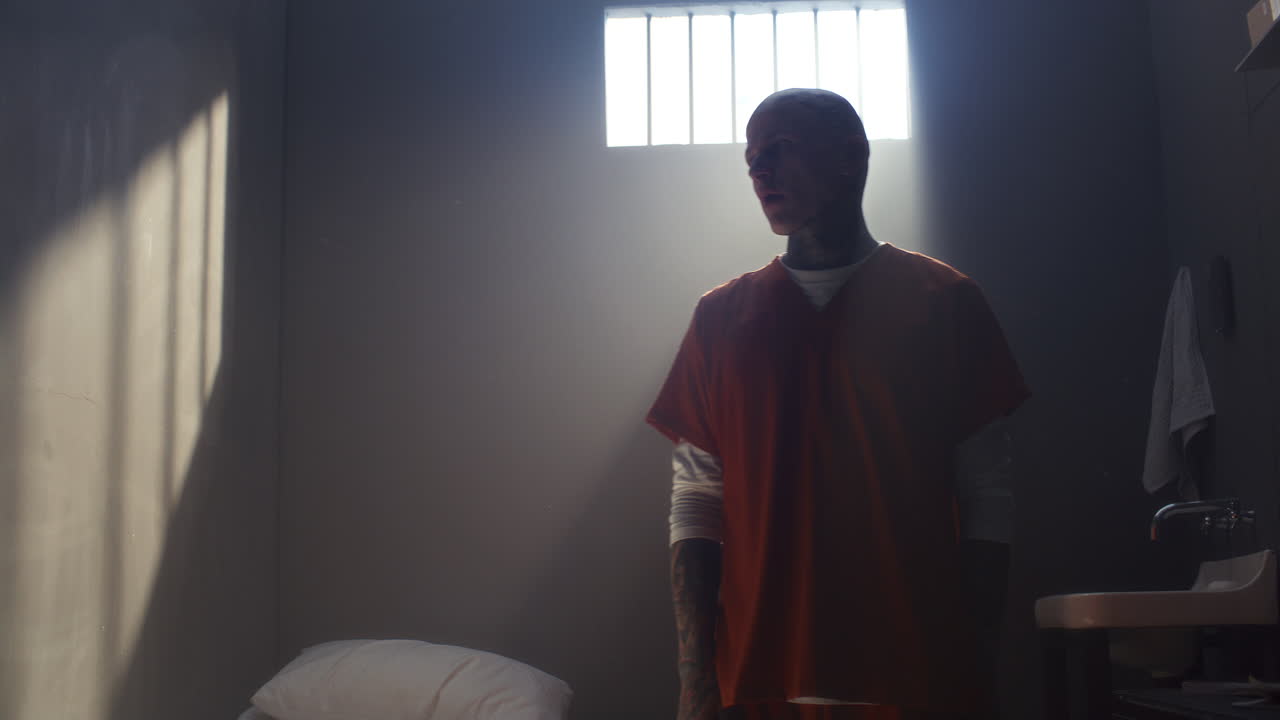 Tattooed Inmate Doing Stretching His Arms and Neck in Prison Cell