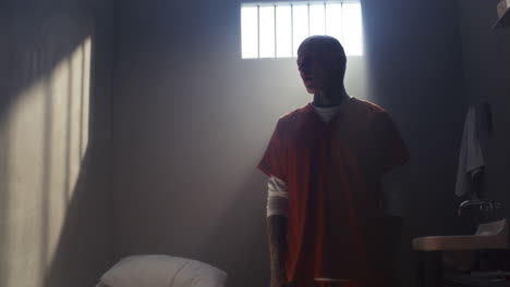 tattooed inmate doing stretching his arms and neck in prison cell