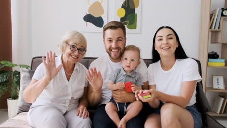 familia feliz sentada en un sofá en la sala de estar saludando y hablando por videollamada