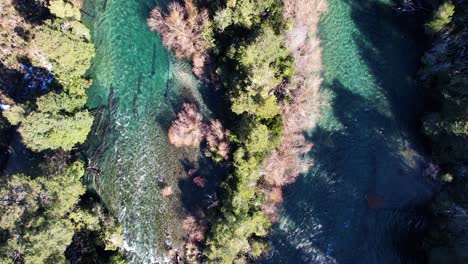 Mountain-river-flowing-surrounded-with-woodland-landscape,-aerial-top-down-view