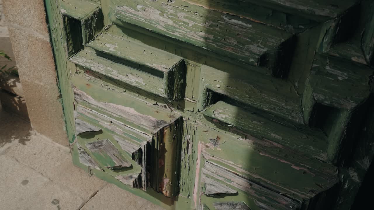 Close up of rustic green wooden door with aged peeling paint details