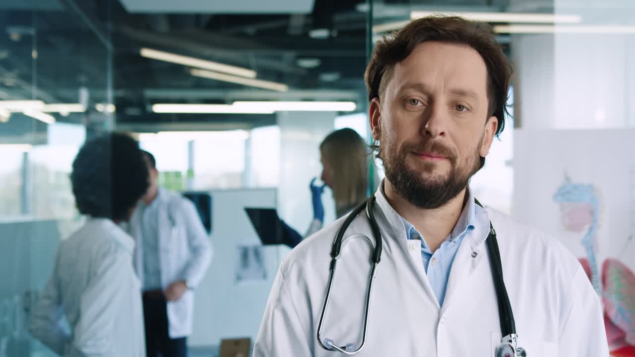 kaukasischer männlicher arzt, der kamera im krankenhausbüro betrachtet