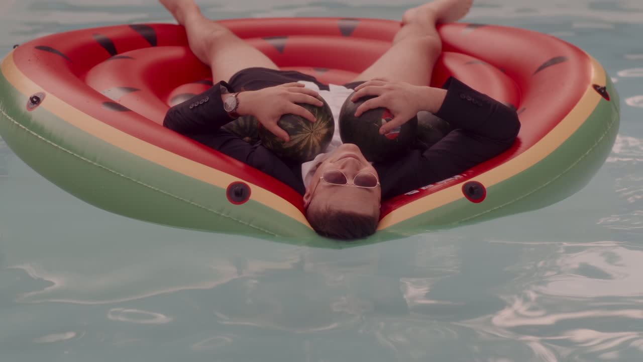 Man relaxing on a watermelon-shaped inflatable pool toy