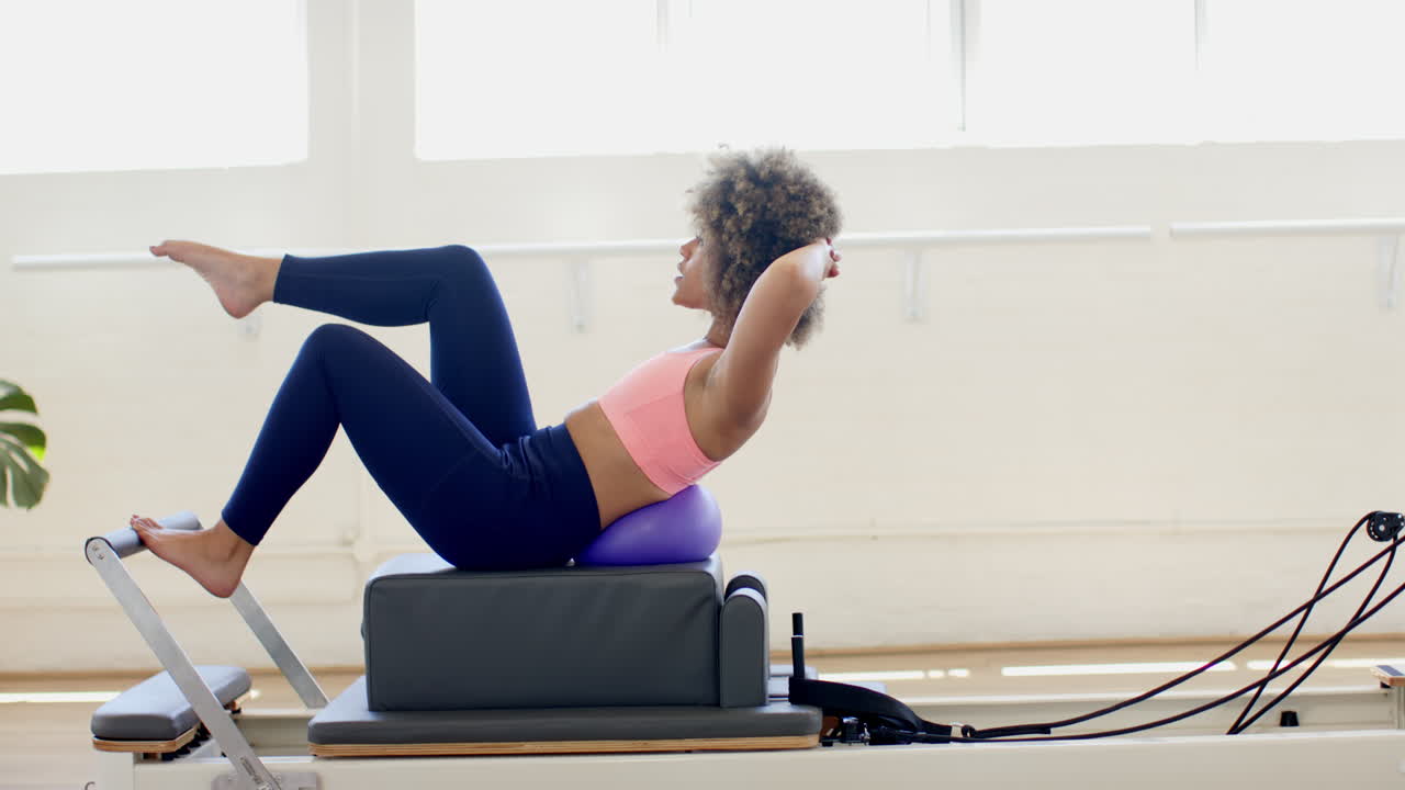 Giovane donna birazziale che si allena su un reformer Pilates
