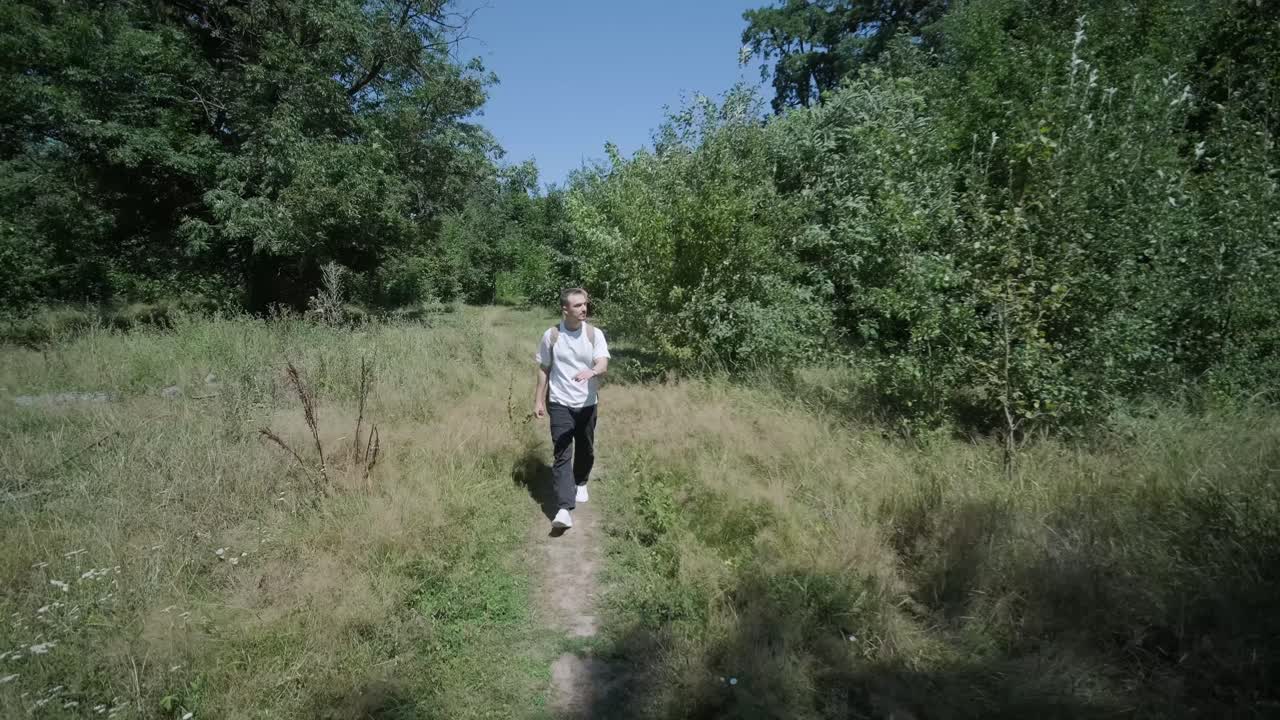 Giovane uomo che cammina con la chitarra per strada vicino a una foresta