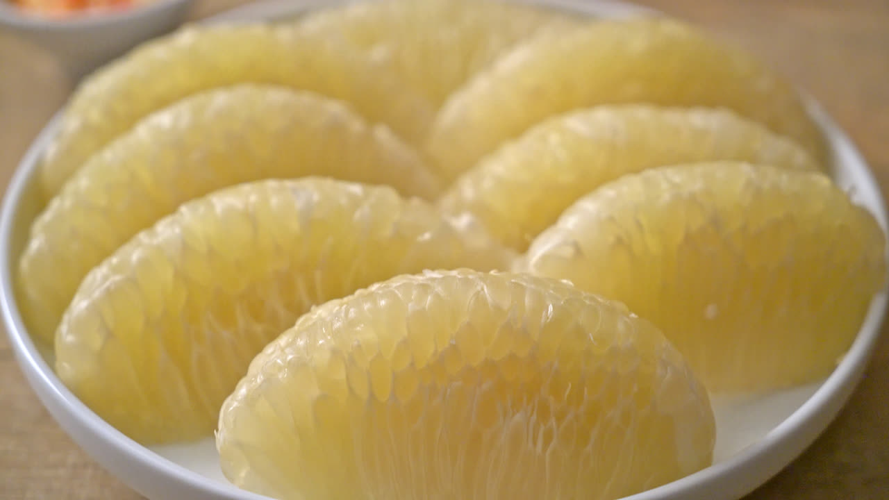 pomelo fresco pelado, pomelo o shaddock en plato blanco