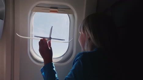 the girl is playing with a small toy airplane in the cabin of the airliner baby dreams concept 4k vi