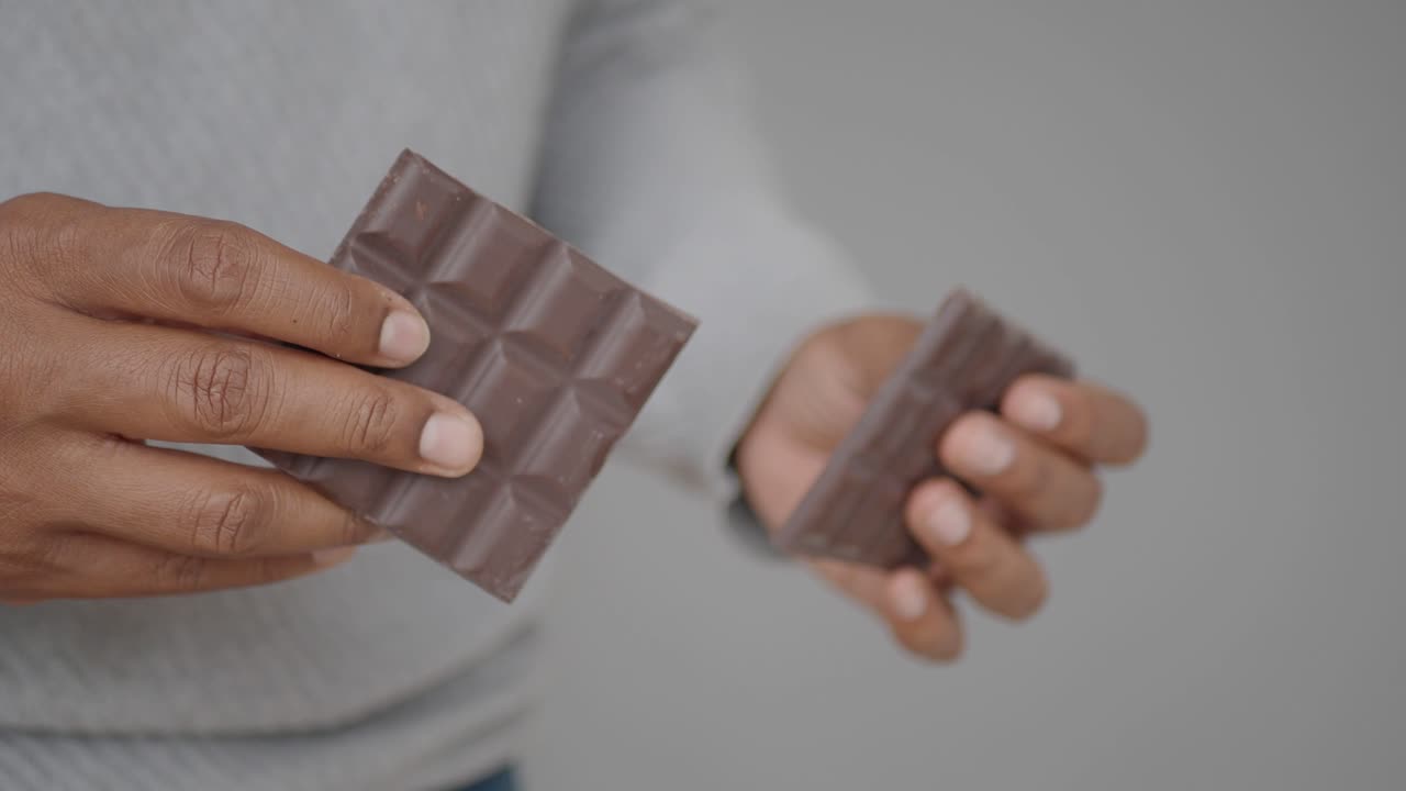 persona que sostiene una barra de chocolate rota