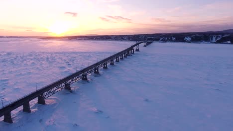 un largo puente cruza un gran río congelado en canadá