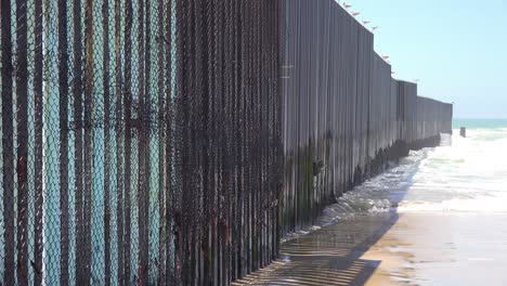 waves roll into the beach at the us mexico border fence in the pacific ocean between san diego and tijuana