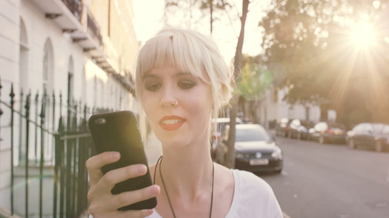 hermosa rubia usando teléfono inteligente en la ciudad