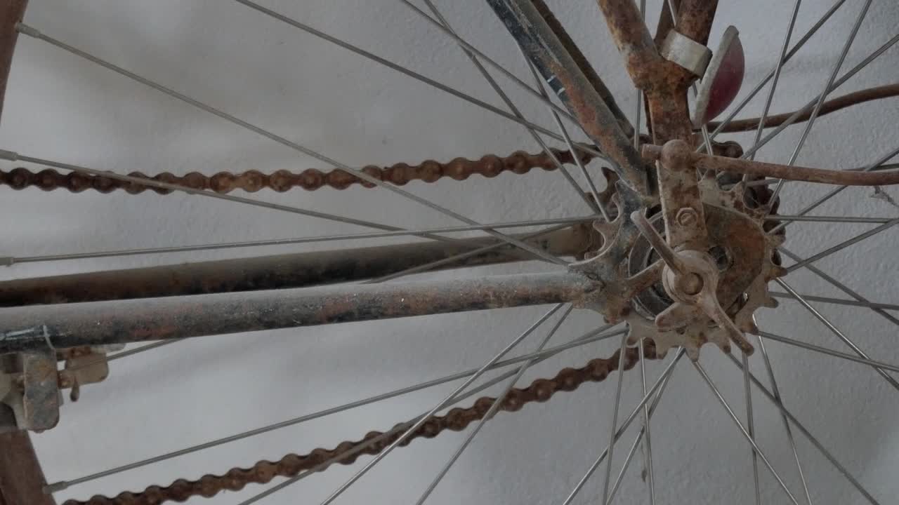 Zoom out of a vintage rusty bicycle wheel with old chain and spokes in detail