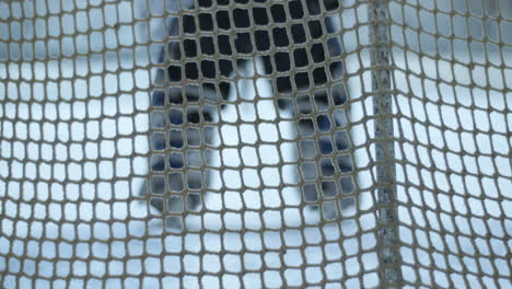 back view of an unrecognizable ice hockey goalkeeper defending net during a match