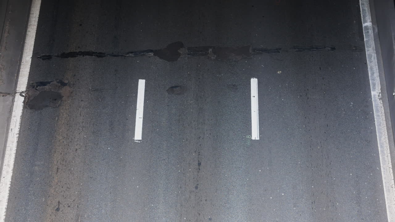 Wide top down traffic timelapse over aged asphalt with white markings and three-lane symmetry