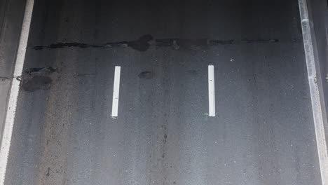 wide top down traffic timelapse over aged asphalt with white markings and three-lane symmetry