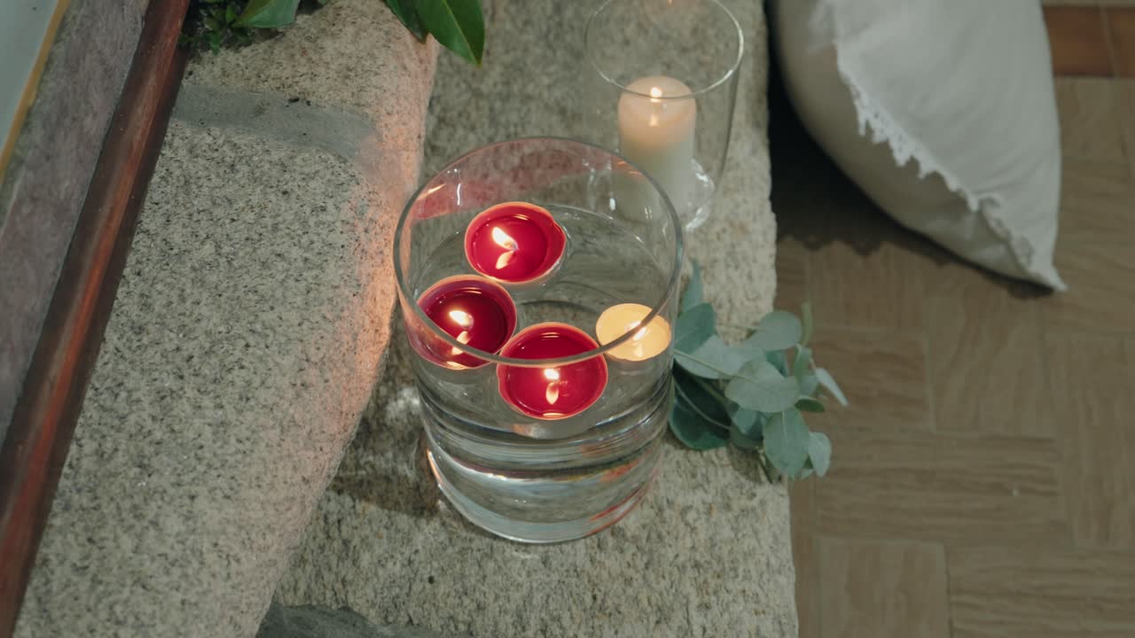 Мягкие светящиеся парящие свечи в стеклянной чаше в уютной обстановке в помещении