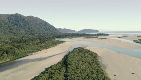 Toma-Aérea-De-Sobrevuelo-De-Una-Playa-Virgen-Junto-A-Un-Acantilado-Boscoso-En-La-Costa-Oeste-De-Nueva-Zelanda