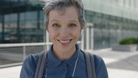 Retrato-De-Una-Mujer-De-Negocios-Madura-Y-Segura,-Sonriendo-Feliz,-Se-Pone-Los-Auriculares-Escuchando-Música-Y-Disfrutando-Al-Salir-Del-Trabajo